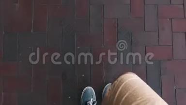 一个穿着短裤和蓝色运动鞋的旅行者走在铺路板上。 电视。